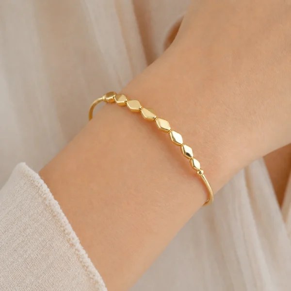 Adjustable gold bracelet Pakistan with geometric leaf-shaped center on a woman's wrist