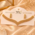 Gold-tone crystal necklace and matching earrings displayed on cream fabric background