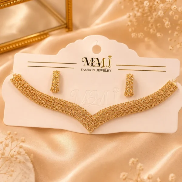 Gold-tone crystal necklace and matching earrings displayed on cream fabric background