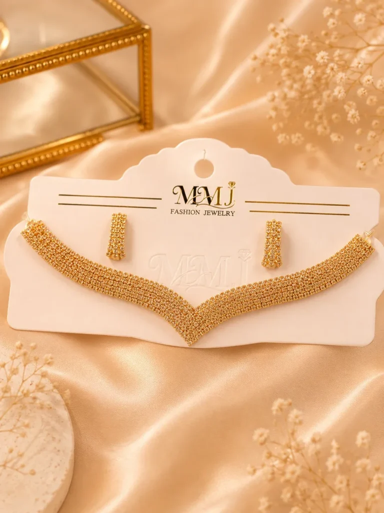 Gold-tone crystal necklace and matching earrings displayed on cream fabric background