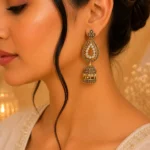 Woman wearing antique gold jhumka earrings with teardrop and dome design