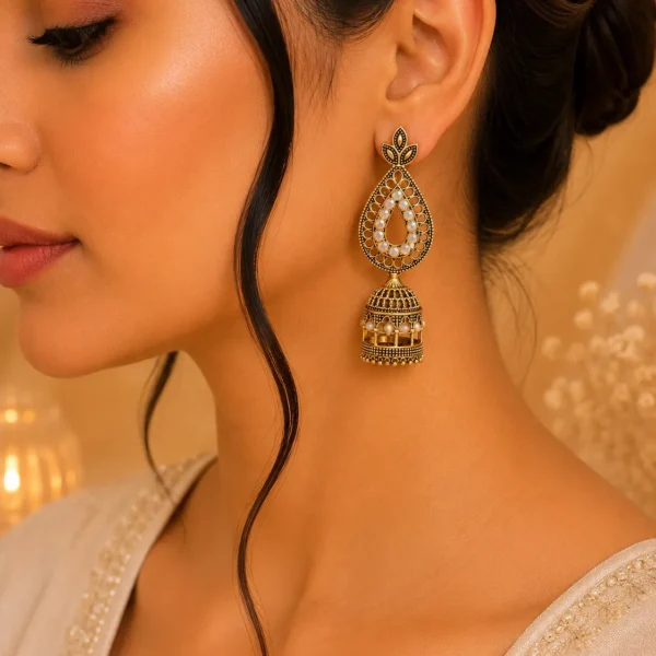 Woman wearing antique gold jhumka earrings with teardrop and dome design