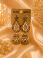 Antique gold-tone jhumka earrings with pearl-style detailing displayed on satin background