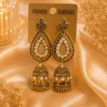 Antique gold-tone jhumka earrings with pearl-style detailing displayed on satin background