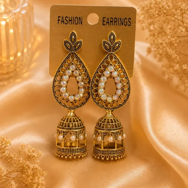 Antique gold-tone jhumka earrings with pearl-style detailing displayed on satin background