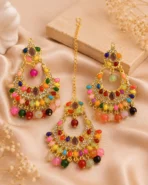 Gold-tone multicolor chandbali earrings with hanging bead detailing displayed on satin background