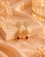 Gold-tone ruby leaf crystal earrings displayed on satin background