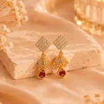 Gold-tone ruby leaf crystal earrings displayed on satin background
