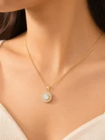 Gold halo pendant necklace with CZ baguette stones on box chain worn by woman