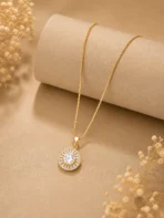 Gold halo pendant necklace with CZ baguette stones on box chain worn by woman