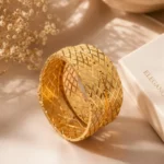 Wide gold bangle pair Pakistan — cross-engraved lattice kangan set worn on wrist by LumiraPK
